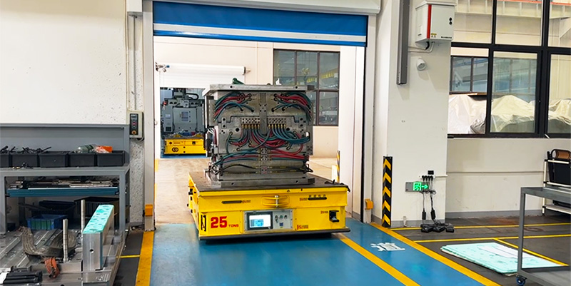 AGV HENSEN с пресс-формой в проёме поднятых автоматических ворот между участками цеха.